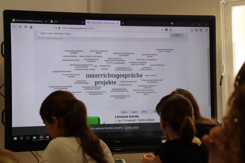 Foto: Studierende sitzen im Seminarraum, am interaktiven Whiteboard wird Answergarden genutzt